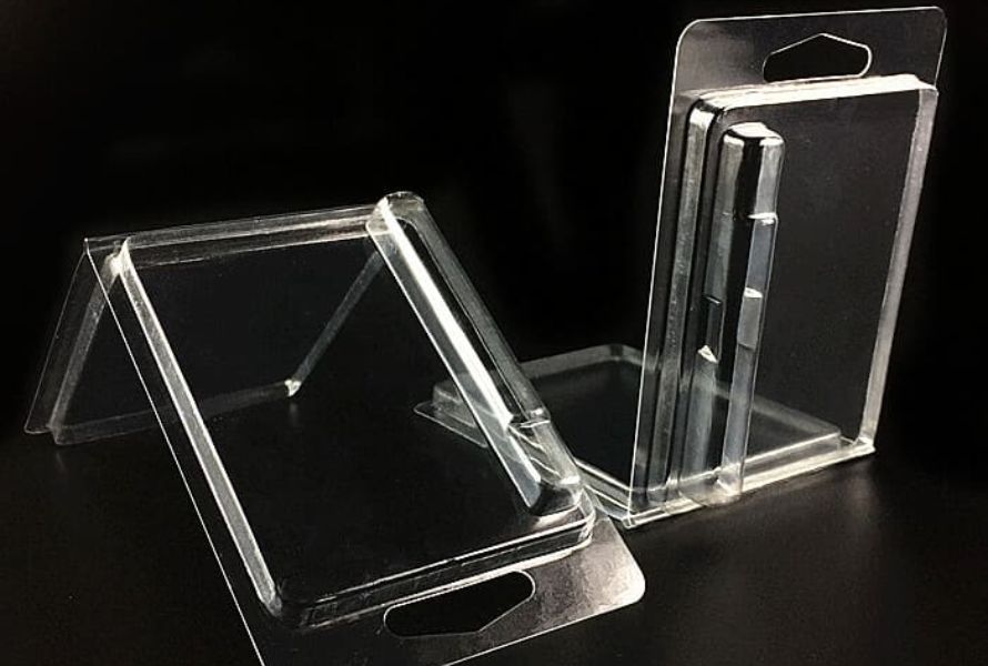 A close-up of clear plastic blister packages being formed on an industrial production line with machinery in the background.