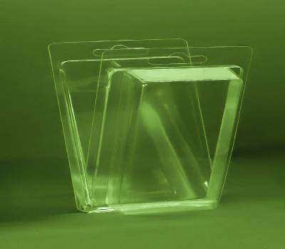 A clear rectangular blister package with a hanging tab, designed for small products, placed on a green surface.